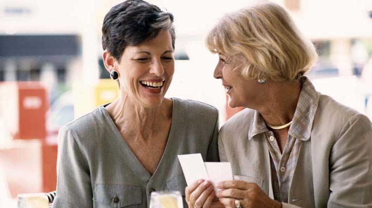 两个上了年纪的女人一边看牌一边愉快地交谈.